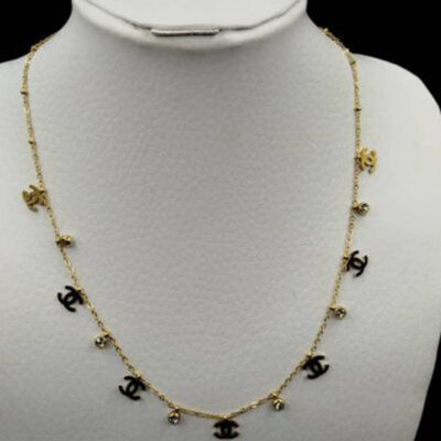Collier chaîne dorée orné de pampilles breloques double C dorées et puces en cristal transparent, porté à la main