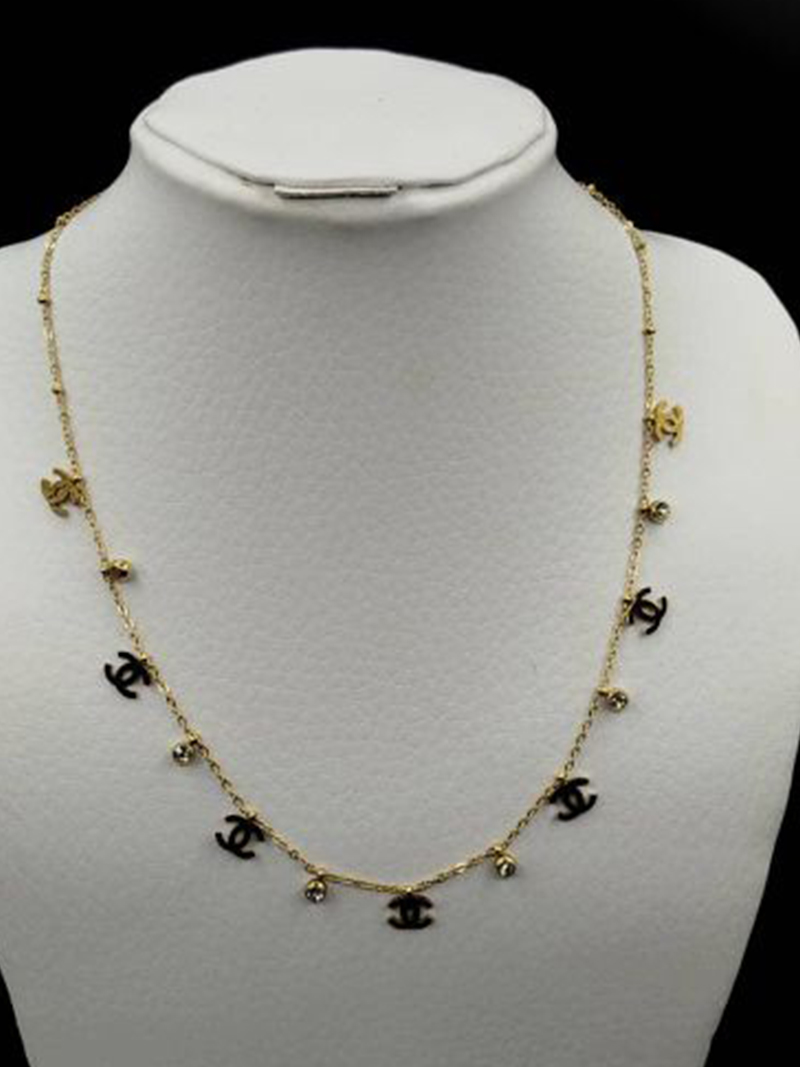 Collier chaîne dorée orné de pampilles breloques double C dorées et puces en cristal transparent, porté à la main
